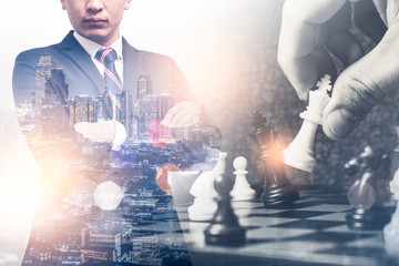 The double exposure image of the businessman standing during sunrise overlay with chess game image. the concept of strategy,intelligence and education.