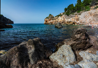 Rocks in the foreground on small mediterranean beach. Mallorca, Spain