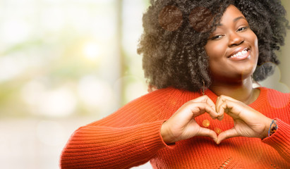 Beautiful african woman happy showing love with hands in heart shape expressing healthy and...