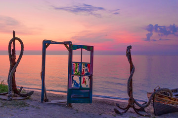 A blue door with colorful glass and anchors on the beach at sunrise, Vama Veche, Black Sea, Romania - obrazy, fototapety, plakaty