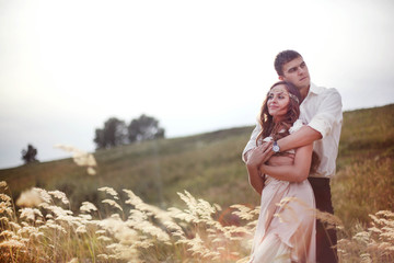 Portrait of beautiful young couple hugging in the gold field. Happy family. Pretty woman and handsome man in love on nature. Sweethearts. Love story