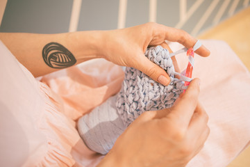Adorable relaxed knitting crochet hobby. Woman in pink dress. leisure creation of clothes. Working woman hands
