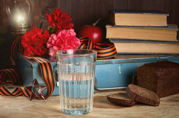 Concept still life of May 9 russian holiday Victory Day. Glass of vodka, rye bread, red carnations,...