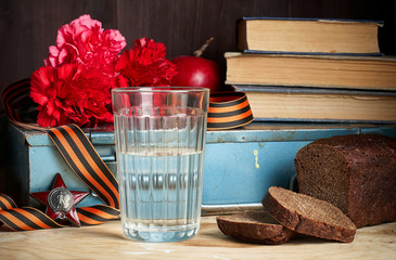 Concept still life of May 9 russian holiday Victory Day. Glass of vodka, rye bread, red carnations,...