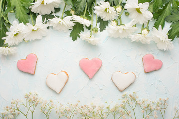 White chrysanthemums on a wooden background, and homemade cookies in the form of hearts
