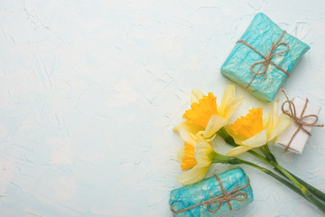 Yellow daffodils with gifts on a wooden background, top view, with empty space for writing or advertising