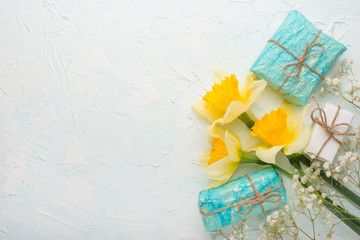 Yellow daffodils with gifts on a wooden background, top view, with empty space for writing or advertising