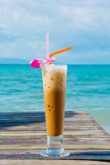 Ice coffee on wooden table with sea background