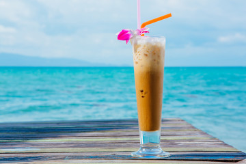 Ice coffee on wooden table with sea background