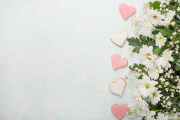 Fototapeta premium White chrysanthemums on a wooden background and homemade cookies in the form of hearts, with an empty space for writing or advertising
