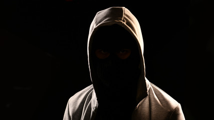 Mysterious man with hoodie on the black background - obrazy, fototapety, plakaty