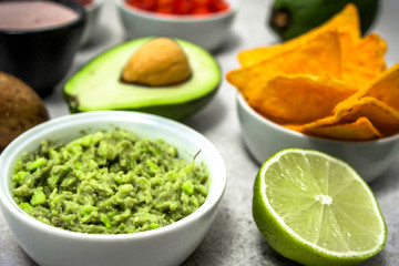 Traditional mexican sauce - guacamole dip with avocado and tortilla chips snack on table, party food for sharing