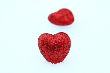 Beautiful red volumetric hearts on white snow. Close-up. Background.