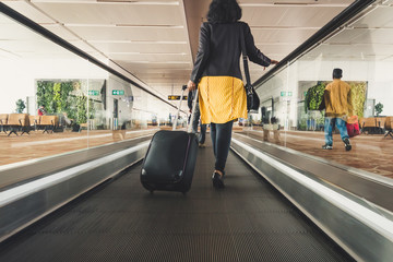 Young girl traveler walking with carrying hold suitcase in the airport.