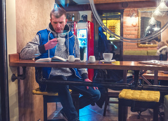 man read the book and drink coffee