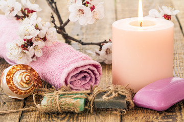 Obraz na płótnie Canvas Soap with towel for bathroom procedures, sea shell and burning candle with flowering branch of apricot tree