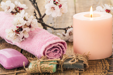 Fototapeta na wymiar Soap with towel for bathroom procedures and burning candle with flowering branch of apricot tree