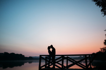 Fototapeta premium Walk the morning of a guy and a girl. Love story on the bridge. Young people by the lake.