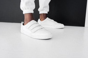 cropped image of stylish african american man standing in white gumshoes