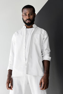 low angle view of handsome stylish african american man looking at camera in white clothes