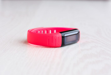 Pink fitness bracelet with place for text on a white wooden background