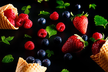 Concept of fresh fruit as alternative to ice cream. Berries fruits spill out of crispy cones wafers.