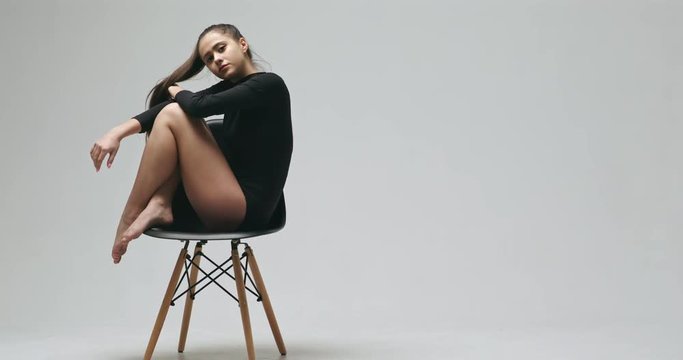 Sensual woman in black bodysuit sitting on chair - slow motion