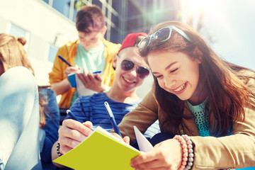 education, high school and people concept - group of happy teenage students with notebooks learning at campus yard