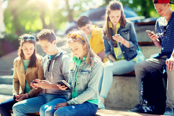 technology, internet addiction and people concept - teenage friends with smartphones outdoors