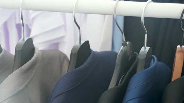 Top down dolly footage of business shirt and suits on a hanger in a store. Available in 4K resolution