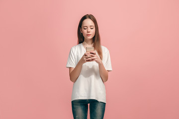 The happy teen girl standing and smiling against pink background.