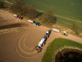 Aerial view of modern Tractor with liquid manure on the agricultural field - prepares it for sowing -  set of equipment for making liquid fertilizer into the soil in the agricultural field 