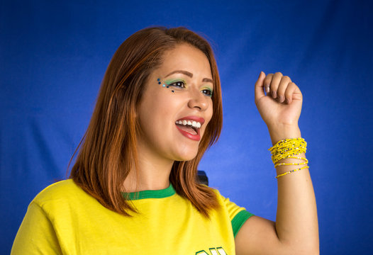 Brazilian woman fan celebrating on football match on blue background.