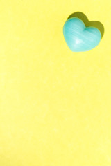 Blue heart shape over yellow table. Valentines day symbol for background use. Love, romance, and passion.