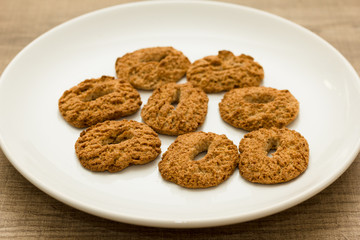 Cookies with a hole, sweet temptation. Dessert on white dish and wooden table. Detail of candy, closeup, selective focus.