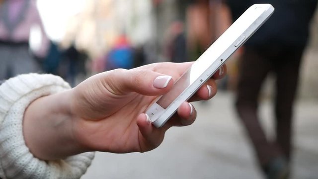 Close-Up Shot Of Woman's Hands Using mobile phone In Busy Public Place