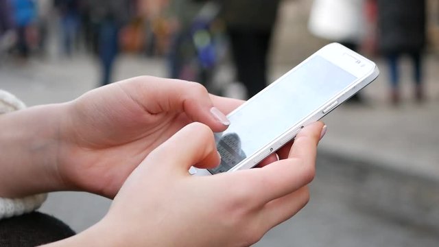 Close-Up Shot Of Woman's Hands Using Mobile Phone In Busy Public Place