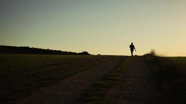 Persona muy feliz saltando de alegr&iacute;a por el campo al atardecer