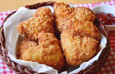 Fried chicken wings are heart-shaped in a basket with ketchup