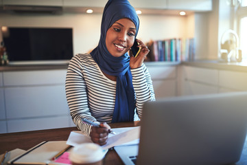 Young Arabic entrepreneur talking on her cellphone and working o