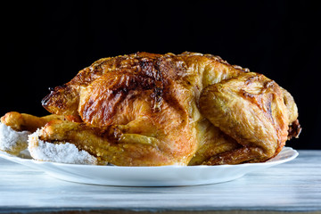 fried chicken whole, on a white plate on a wooden background