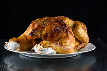 fried chicken whole, on a white plate on a wooden background