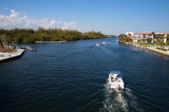 Boats Pass The Intracoastal Waterway Bridge Just North Of Hillsboro Blvd. In Deerfield Beach, Florida In A Bright Sunny Afternoon With The Boca Raton Hotel And Resort In The Background