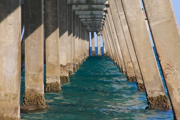 Underside of Deerfield Beach, Florida Pier with the Sun Revealing Concrete Supports and Water Lapping Underneath in Late Afternoon