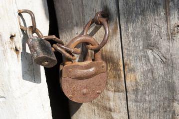 Old rusty metal lock on old wooden door. Rusty chain