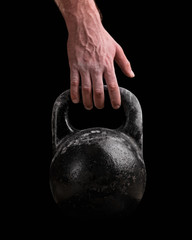Fototapeta premium Kettlebell in a man's hand on a black background