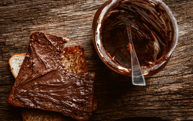 Empty can of chocolate paste with a spoon inside and bitten toast bread with chocolate paste spread on it