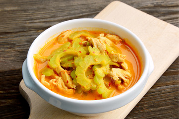 Thai Chicken Curry with Bitter Gourd in white bowl on wooden background.
Chinese bitter melon with coconut and curry soup