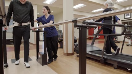 Medium shot of a senior man walking in parallel bars - Powered by Adobe