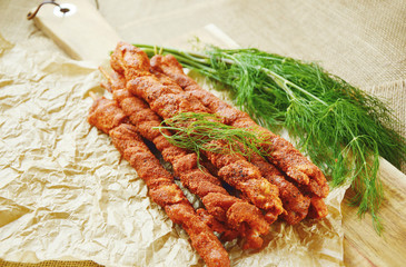 BBQ Pork Belly Strips with Spicy powder and Dill on white paper and wooden broad on sack background